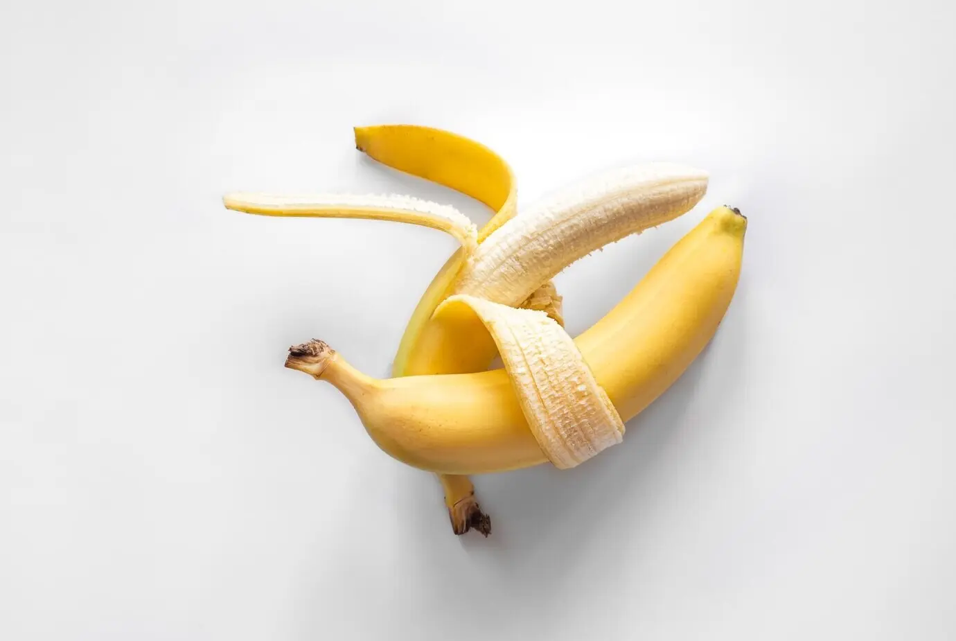 Zwei Bananen auf weißem Hintergrund, freigestellt, konzeptueller Minimalismus.