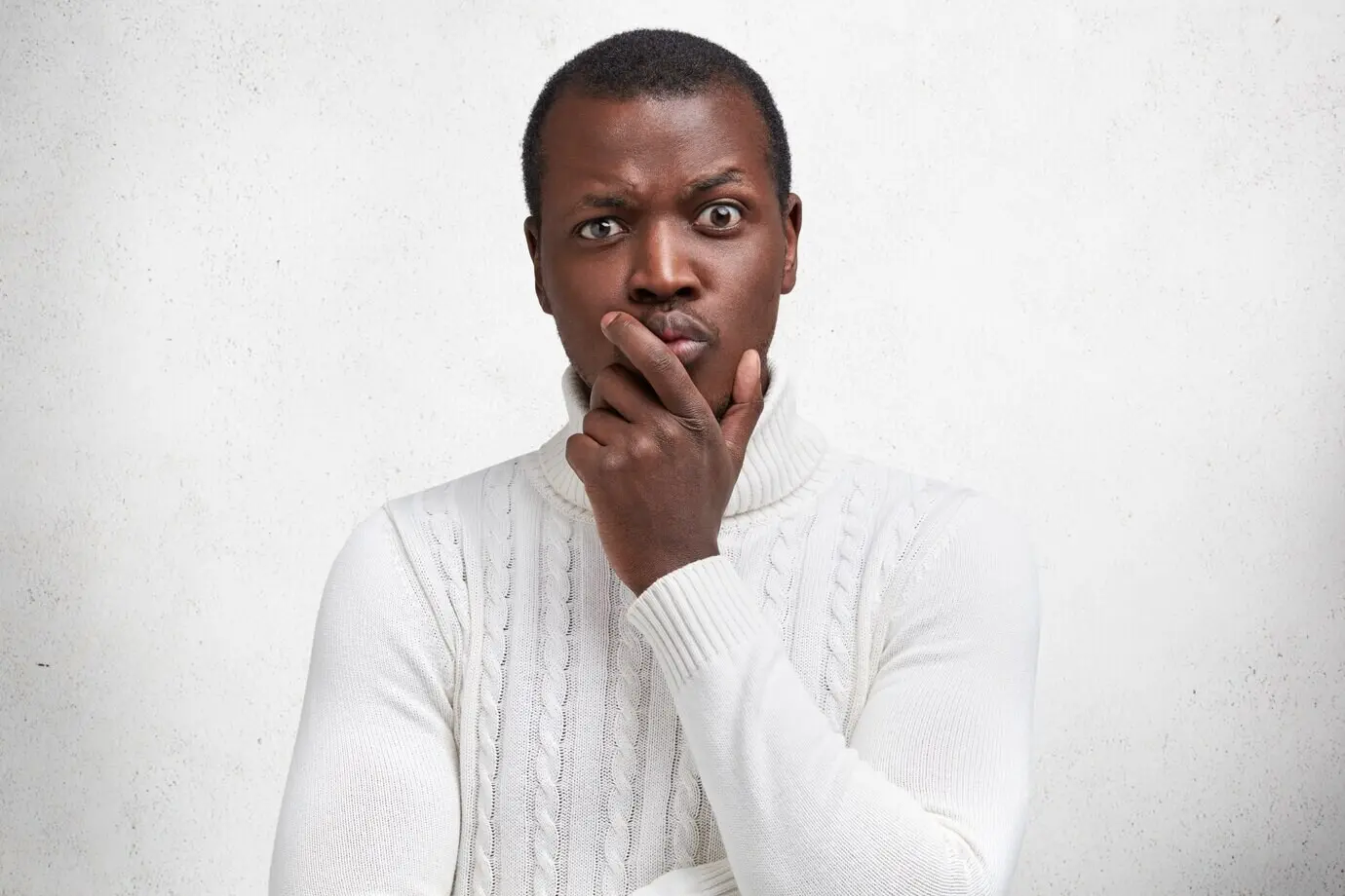 Ein gutaussehender, dunkelhäutiger, männlicher Kunstkenner betrachtet im Museum sorgfältig ein Bild, würdigt das Meisterwerk und hat einen nachdenklichen Gesichtsausdruck.