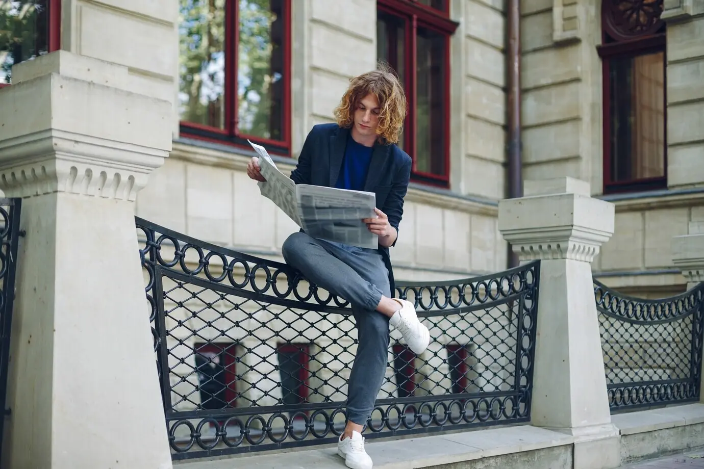 Ein Mann liest eine Zeitung in der Nähe eines Gebäudes im alten Stil.